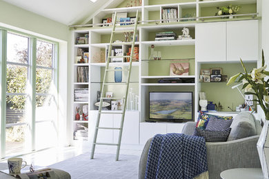 Foto di un soggiorno minimal aperto e di medie dimensioni con libreria, pareti verdi, parquet chiaro, parete attrezzata, pavimento bianco e tappeto