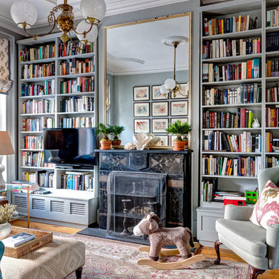 Mid-sized ornate medium tone wood floor family room library photo in New York with green walls and a stone fireplace