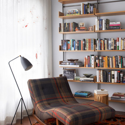 Trendy medium tone wood floor and brown floor family room library photo in New York with white walls