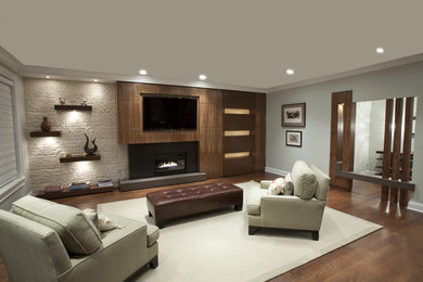 Ejemplo de sala de estar cerrada contemporánea grande con suelo de madera en tonos medios, chimenea lineal, pared multimedia, paredes grises y marco de chimenea de metal