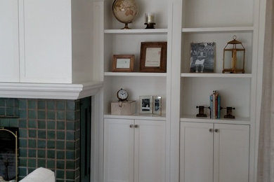 Ejemplo de sala de estar tradicional con paredes blancas, suelo de madera en tonos medios, todas las chimeneas, marco de chimenea de baldosas y/o azulejos y televisor retractable
