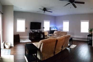 Ejemplo de sala de estar cerrada tradicional de tamaño medio sin chimenea con paredes beige, suelo de madera en tonos medios y televisor colgado en la pared