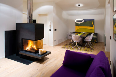 Foto de sala de estar abierta contemporánea grande sin televisor con paredes blancas, suelo de madera clara, chimenea de doble cara y marco de chimenea de metal