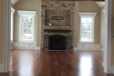 Inspiration for a mid-sized timeless enclosed dark wood floor family room remodel in Other with beige walls, a standard fireplace, a stone fireplace and a media wall