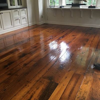 Example of a mid-sized mountain style medium tone wood floor family room design in Newark with white walls and a media wall
