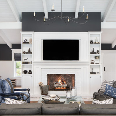Large beach style open concept medium tone wood floor and brown floor family room photo in Miami with black walls, a standard fireplace, a brick fireplace and a wall-mounted tv