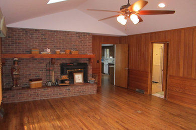 Ejemplo de sala de estar cerrada tradicional de tamaño medio con paredes marrones, todas las chimeneas y marco de chimenea de ladrillo