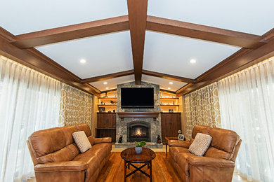 Mid-sized elegant open concept medium tone wood floor and brown floor family room photo in Other with brown walls, a standard fireplace, a stone fireplace and a wall-mounted tv