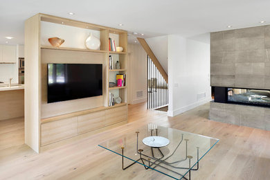 Mittelgroßes, Offenes Modernes Wohnzimmer mit weißer Wandfarbe, hellem Holzboden, Tunnelkamin, Kaminumrandung aus Stein und Multimediawand in Toronto