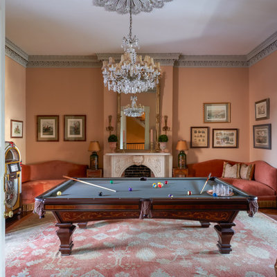 Inspiration for a victorian enclosed medium tone wood floor and brown floor family room remodel in New Orleans with orange walls