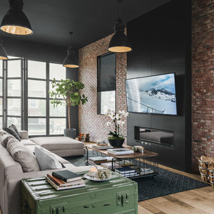 Offenes, Großes Industrial Wohnzimmer mit schwarzer Wandfarbe, Wand-TV, Gaskamin, Kaminumrandung aus Metall und Laminat