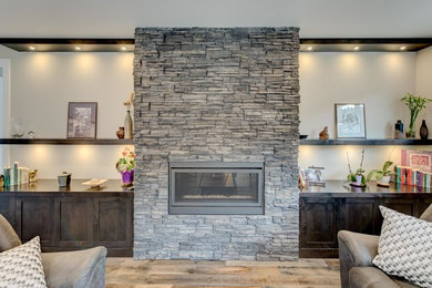 バンクーバーにある高級な中くらいなトランジショナルスタイルのおしゃれなオープンリビング (グレーの壁、無垢フローリング、横長型暖炉、石材の暖炉まわり、テレビなし) の写真