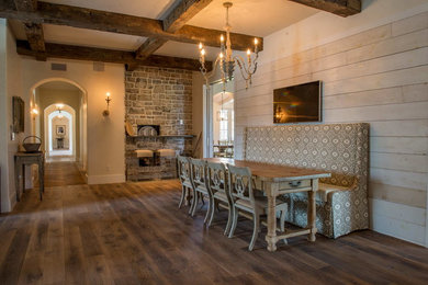 Example of a large tuscan medium tone wood floor dining room design in Other with a stone fireplace