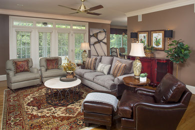 Imagen de sala de estar cerrada tradicional renovada de tamaño medio con paredes marrones, suelo de madera clara, todas las chimeneas y televisor colgado en la pared