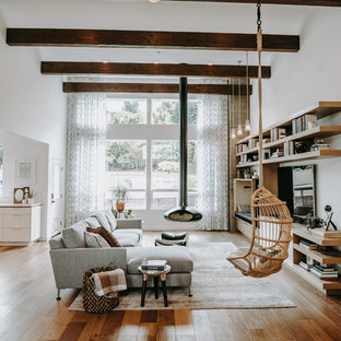 Modernes Wohnzimmer mit weißer Wandfarbe, braunem Holzboden, Hängekamin, Wand-TV und braunem Boden in Seattle