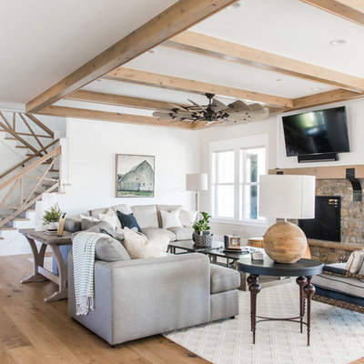 Example of a beach style open concept light wood floor family room design in Salt Lake City with white walls, a standard fireplace, a stone fireplace and a wall-mounted tv