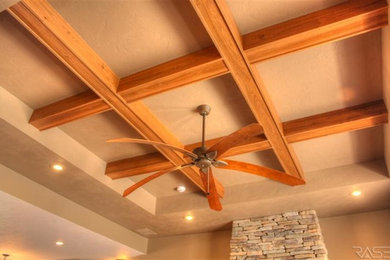 Imagen de sala de estar de estilo americano de tamaño medio con paredes beige, suelo de madera en tonos medios, todas las chimeneas y marco de chimenea de piedra