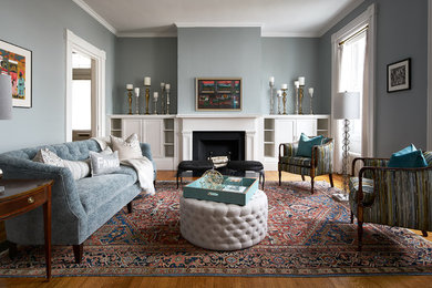Imagen de sala de estar cerrada clásica renovada con paredes grises, suelo de madera en tonos medios, todas las chimeneas y alfombra