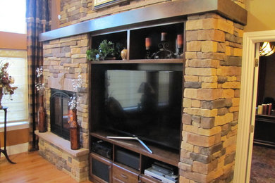 デンバーにある広いラスティックスタイルのおしゃれなオープンリビング (ベージュの壁、無垢フローリング、標準型暖炉、石材の暖炉まわり、埋込式メディアウォール) の写真