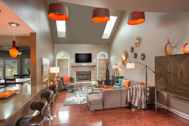 Family room - mid-sized modern open concept medium tone wood floor family room idea in Columbus with a bar, a standard fireplace, a stone fireplace, a wall-mounted tv and gray walls