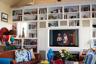 Example of an eclectic family room library design in Los Angeles with beige walls and a media wall