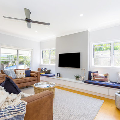 Family room - contemporary medium tone wood floor family room idea in Other with gray walls, no fireplace and a wall-mounted tv