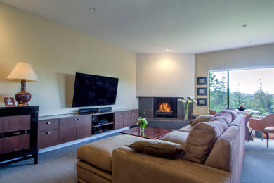 Imagen de sala de estar cerrada actual grande con paredes beige, moqueta, chimenea de esquina y televisor colgado en la pared