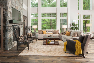 Diseño de sala de estar abierta tradicional renovada grande sin chimenea con paredes grises, suelo de madera oscura, televisor colgado en la pared y suelo marrón