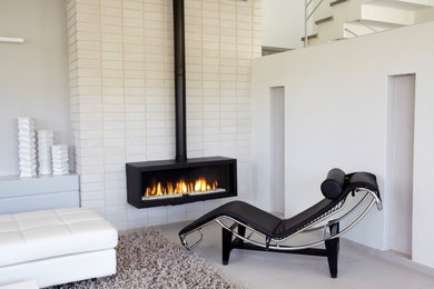 Imagen de sala de estar contemporánea de tamaño medio con paredes blancas, suelo de baldosas de porcelana, chimeneas suspendidas y marco de chimenea de ladrillo