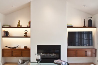 Ejemplo de sala de estar con rincón musical abierta contemporánea de tamaño medio con paredes blancas, suelo de madera clara, chimenea lineal, marco de chimenea de yeso y televisor colgado en la pared