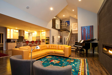 На фото: открытая гостиная комната в современном стиле с темным паркетным полом, фасадом камина из штукатурки, горизонтальным камином, телевизором на стене и серыми стенами с