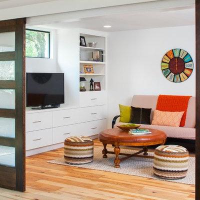 Example of a trendy enclosed medium tone wood floor family room design in Austin with white walls and a tv stand