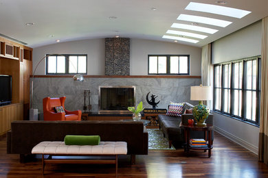Modelo de sala de estar abierta clásica renovada grande con pared multimedia, suelo de madera en tonos medios, paredes grises, todas las chimeneas y marco de chimenea de metal