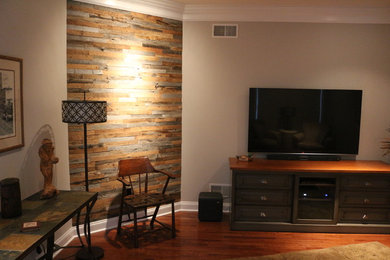 Ejemplo de sala de estar cerrada actual de tamaño medio sin chimenea con paredes grises, suelo de madera en tonos medios y televisor colgado en la pared