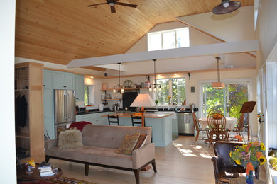 Diseño de sala de estar abierta de estilo de casa de campo de tamaño medio sin chimenea con paredes amarillas y suelo de madera clara