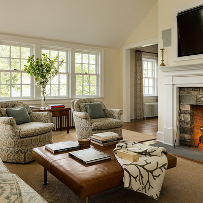 Inspiration for a timeless dark wood floor family room remodel in New York with beige walls, a standard fireplace, a stone fireplace and a wall-mounted tv
