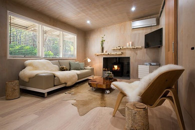 Foto de sala de estar abierta rural pequeña con paredes grises, suelo de madera en tonos medios, todas las chimeneas y televisor colgado en la pared