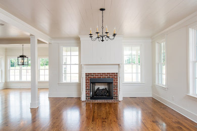 Modelo de sala de estar abierta de estilo de casa de campo de tamaño medio con suelo de madera en tonos medios, todas las chimeneas y marco de chimenea de ladrillo