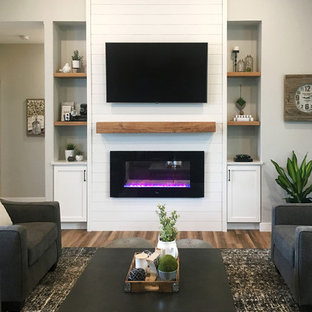 Großes, Offenes Country Wohnzimmer mit grauer Wandfarbe, dunklem Holzboden, Gaskamin, Kaminumrandung aus Holz, Wand-TV und braunem Boden in Sonstige