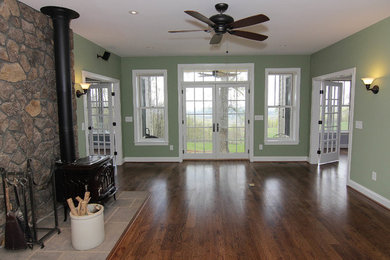 Idee per un soggiorno stile americano di medie dimensioni con pareti verdi, pavimento in legno massello medio e cornice del camino in pietra