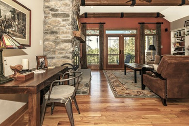 Diseño de sala de estar abierta de estilo americano grande con paredes multicolor, suelo de madera clara, todas las chimeneas, marco de chimenea de piedra y televisor independiente