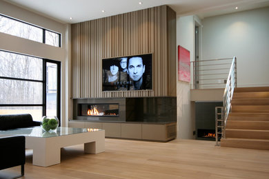 Ejemplo de sala de estar abierta contemporánea grande con paredes blancas, suelo de madera clara, chimenea lineal, marco de chimenea de piedra y pared multimedia