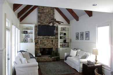 Example of a mid-sized classic enclosed dark wood floor and brown floor family room design in Atlanta with white walls, a standard fireplace, a stone fireplace and a wall-mounted tv