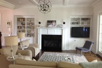 Imagen de sala de estar cerrada clásica renovada de tamaño medio con paredes blancas, suelo de madera en tonos medios, todas las chimeneas, marco de chimenea de metal, televisor colgado en la pared y suelo beige