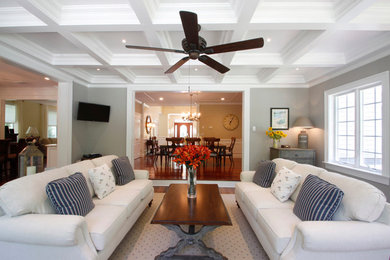Diseño de sala de estar abierta clásica grande con suelo de madera en tonos medios, paredes grises y televisor colgado en la pared