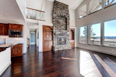 Large rustic open plan games room in Denver with dark hardwood flooring, a standard fireplace, a stone fireplace surround, grey walls and a built-in media unit.