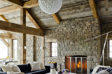 Ejemplo de sala de estar abierta rústica grande con paredes beige, todas las chimeneas y marco de chimenea de piedra
