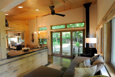 Ejemplo de sala de estar abierta rural de tamaño medio sin televisor con paredes beige, suelo de cemento, estufa de leña y marco de chimenea de metal