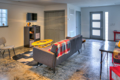 Modelo de sala de estar con barra de bar cerrada de estilo americano de tamaño medio con paredes grises, suelo de cemento, televisor colgado en la pared y suelo gris