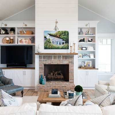 Example of a beach style open concept light wood floor family room design in Wilmington with blue walls, a standard fireplace, a brick fireplace and a media wall
